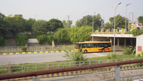 city metro bus in motion: exiting underpass, surrounded by vibrant green spaces and urban landscapes