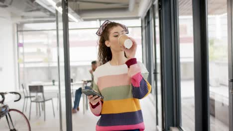 Portrait-of-biracial-businesswoman-walking-with-coffee-in-office-in-slow-motion