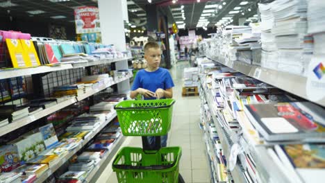 VINNITSA, UKRAINE - AUGUST 20, 2018: Little boy is buying stationery for school. Back to school concept.