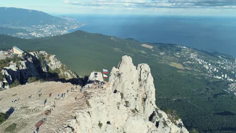 aerial view of a mountain peak with people and russian flag