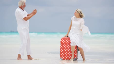 barefoot mature caucasian couple with suitcase and camera