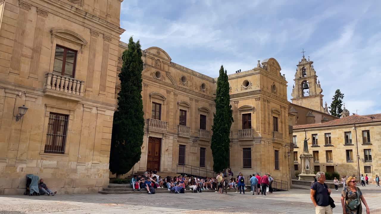 In the afternoon filming of the main façade of the Episcopal Palace located on the west side of the cathedral with its 2 green and tall cypresses and a large group of tourists sitting on its steps.