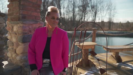 Strong-Attractive-Woman-In-Pink-Coat-Sitting,-Posing-And-Smiling-At-Camera