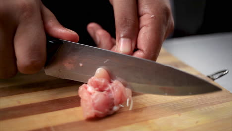 hombres cortando alitas de pollo crudas con un cuchillo afilado y formando una piruleta en una tabla de cortar para cocinar