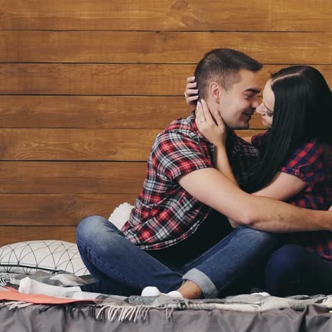 happy young couple in plaid shirts are hugging on the bedroom on st. valentine's day