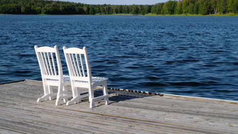white chairs on a dock by a lake
