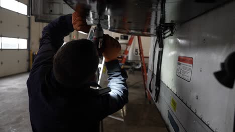 mecánico que utiliza una llave de impacto inalámbrica para atar una cubierta de un remolque refrigerado