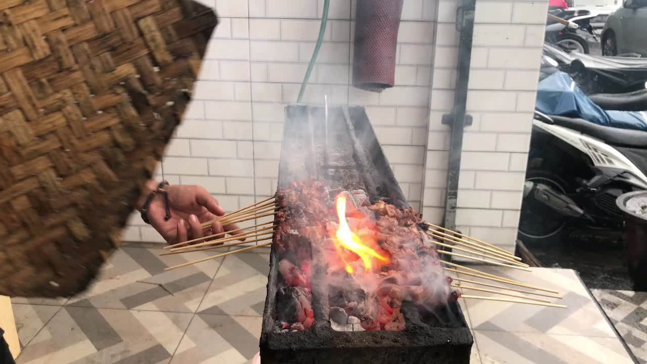 el vendedor de satay cocina brochetas de cabra a la parrilla y usa fuego de carbón para que la carne tenga un delicioso aroma a skokey.