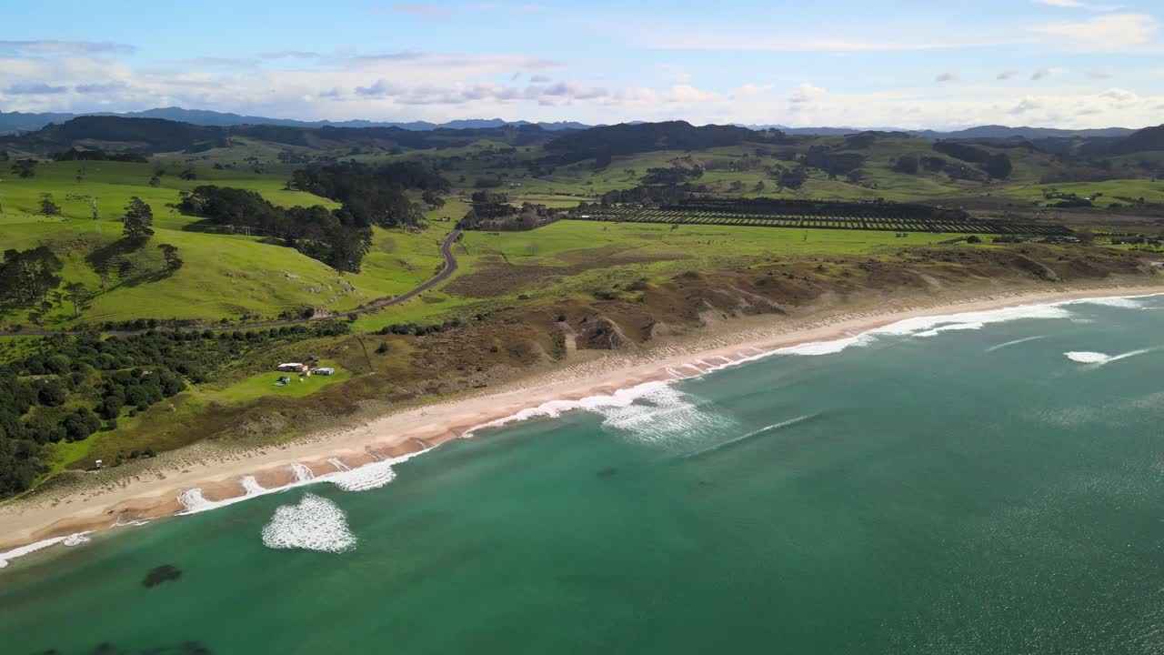 vista aérea de hahei, playa de agua caliente en el coromandel con colinas onduladas detrás