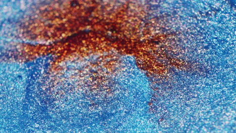 a water drop hits glittery red and blue ink in macro slow motion, creating ripples and shimmering movement