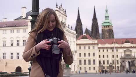 Photographer-girl-checking-photos-in-camera,-Prague-castle-in-background,-Czech-Republic