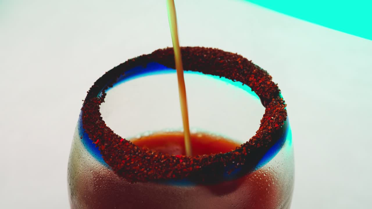 Versare succo di pomodoro in un bicchiere ghiacciato