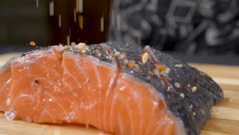 a close up shot in slow motion of a piece of raw fish being salted ready to be cooked