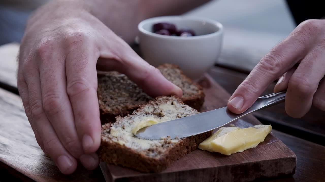 Man butters a piece of artisan whole grain bread