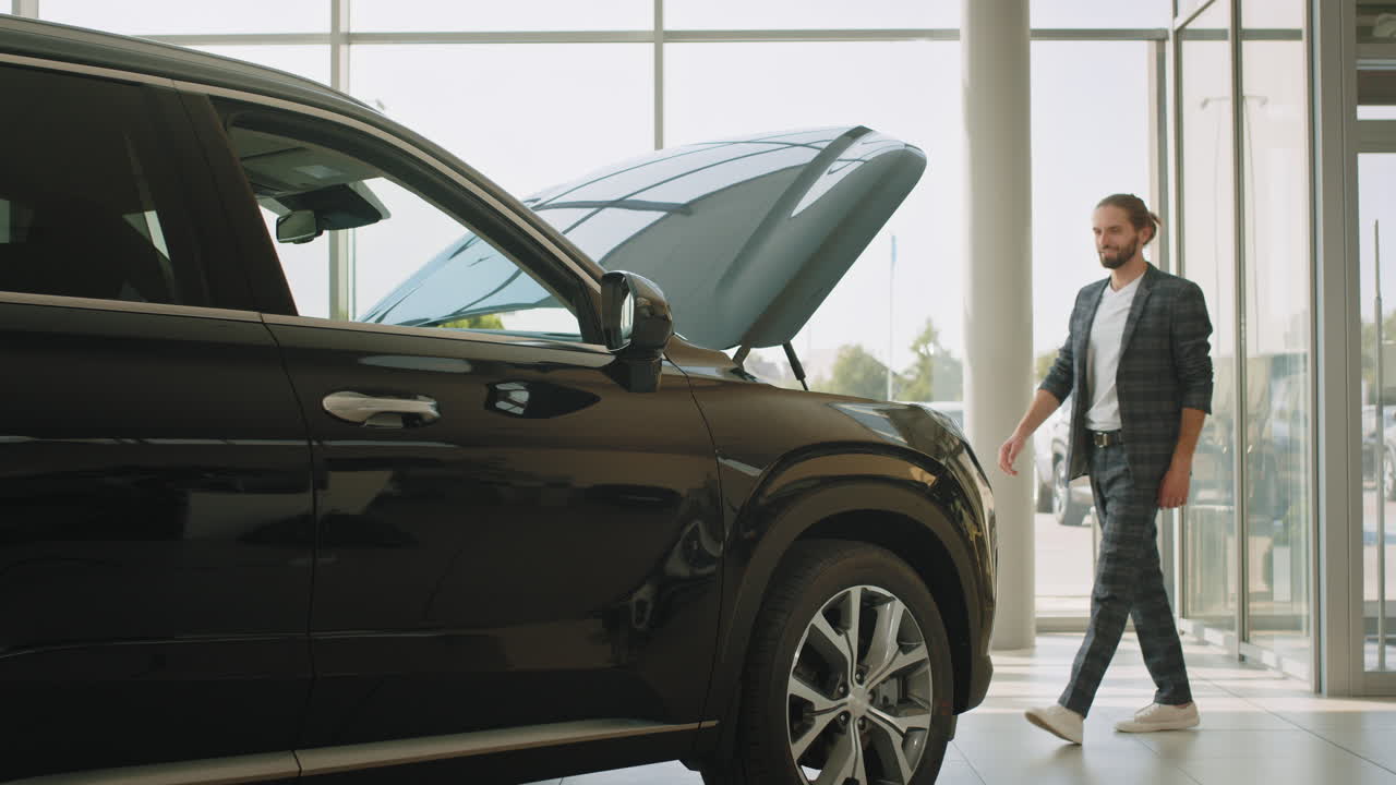 러에서 검은 suv의 후드를 확인하는 남자