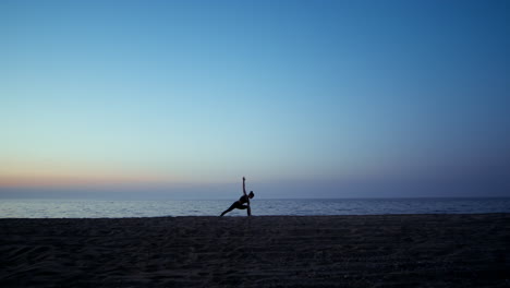 silhouette yoga woman training warrior asana in front beautiful sunset sky.