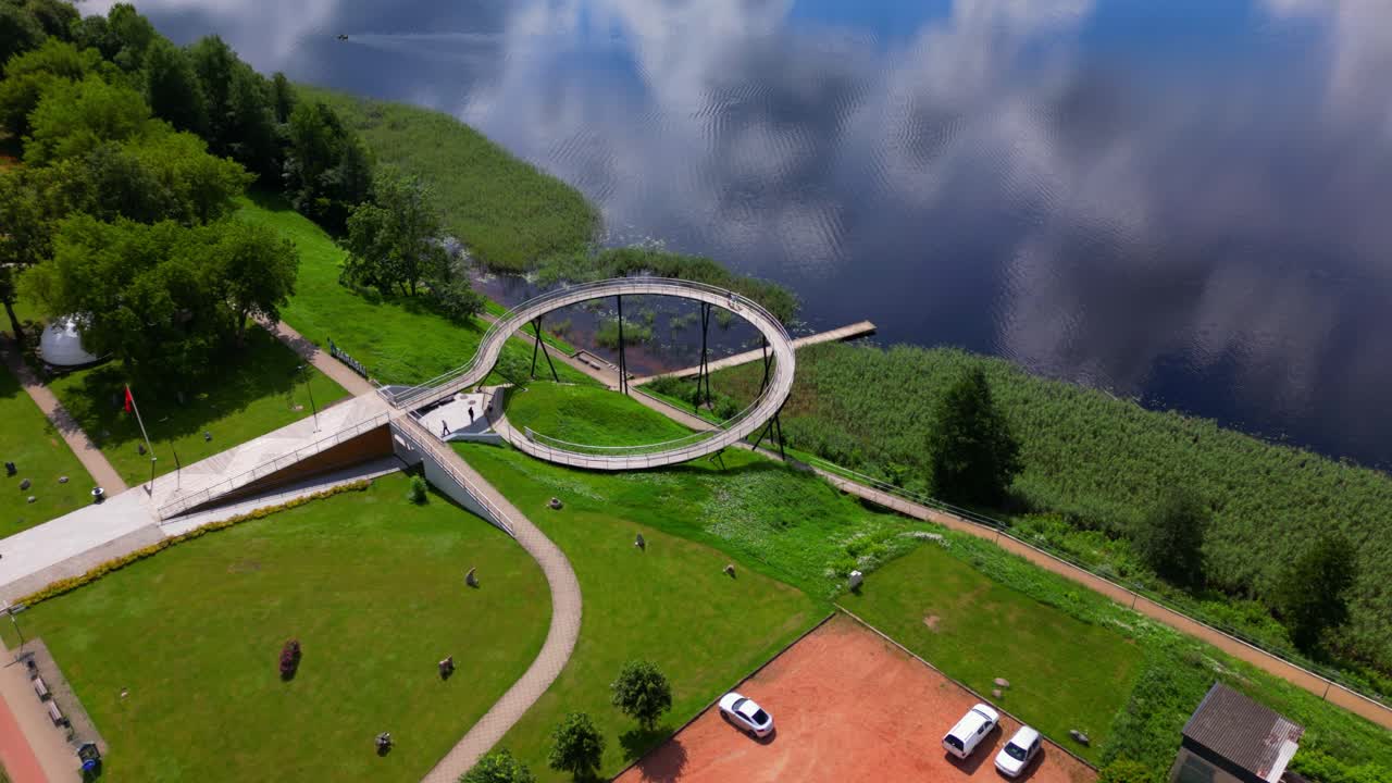 Aerial view of a circular pier extending over a serene lake, surrounded by park greenery and walking paths. Shot at Zarasai, Lithuania (Zarasai, Lietuva)
