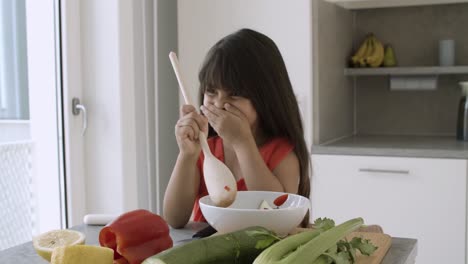 adorable little girl cooking salad by herself