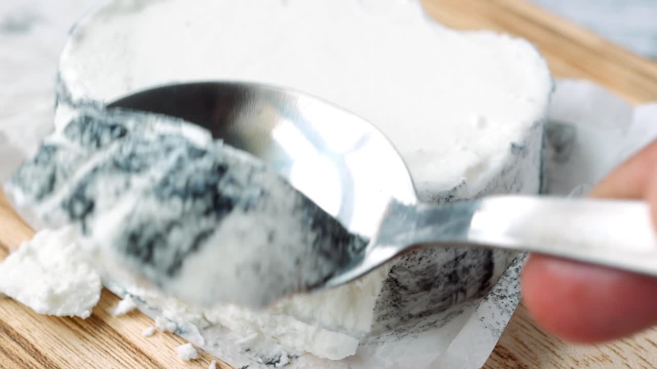 Cutting fresh goat cheese with a spoon ,