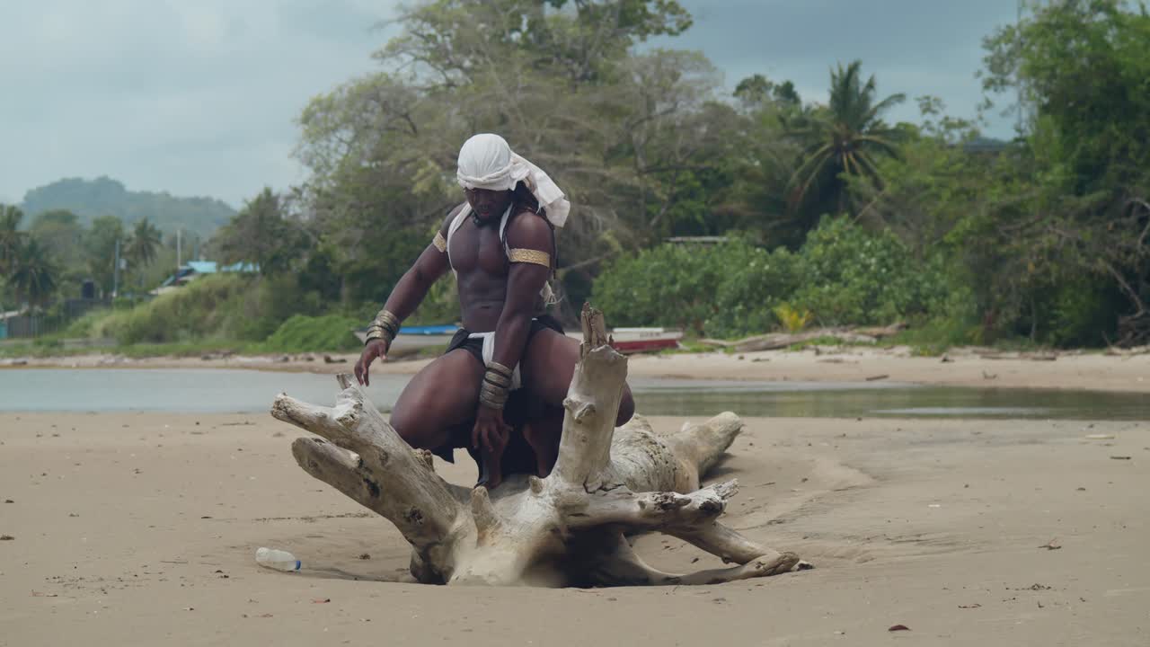 Dark skin and muscles on a male cosplayer at the beach on a log