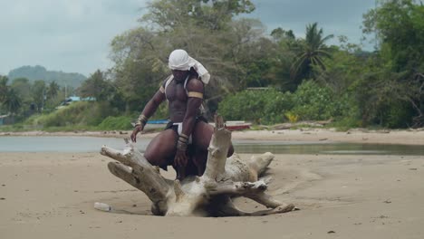 dark skin and muscles on a male cosplayer at the beach on a log