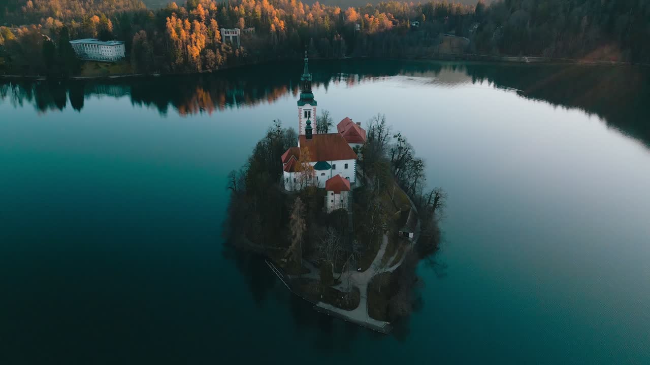 Un delicato movimento aereo svela l'isola con la chiesa storica nel Lago di Bled. La chiesa è bagnata dal sole mattutino