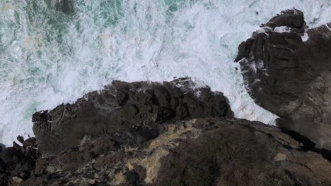 Movimiento-Deslizante-Desde-Un-Dron-Sobrevolando-La-Costa-Rocosa-Con-Vista-De-Arriba-Hacia-Abajo,-Olas-Del-Mar-Que-Conducen-A-Ella