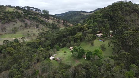 Drone-movement-around-a-beautiful-mountain-full-of-trees-and-small-houses,-nature