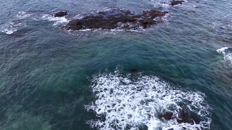 Ripresa aerea con drone dall'alto di onde turchesi che si infrangono contro scogliere rocciose a Flinders, Australia