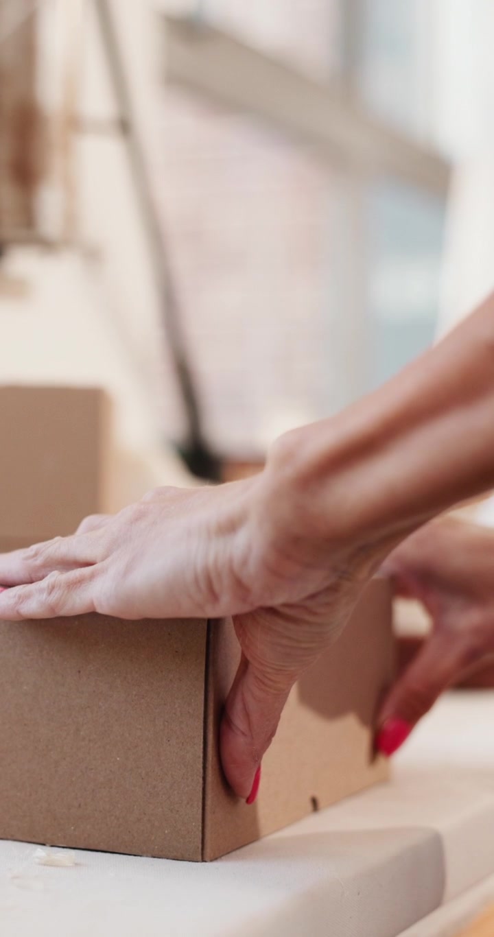 Person Assembling a Cardboard Box for Shipping