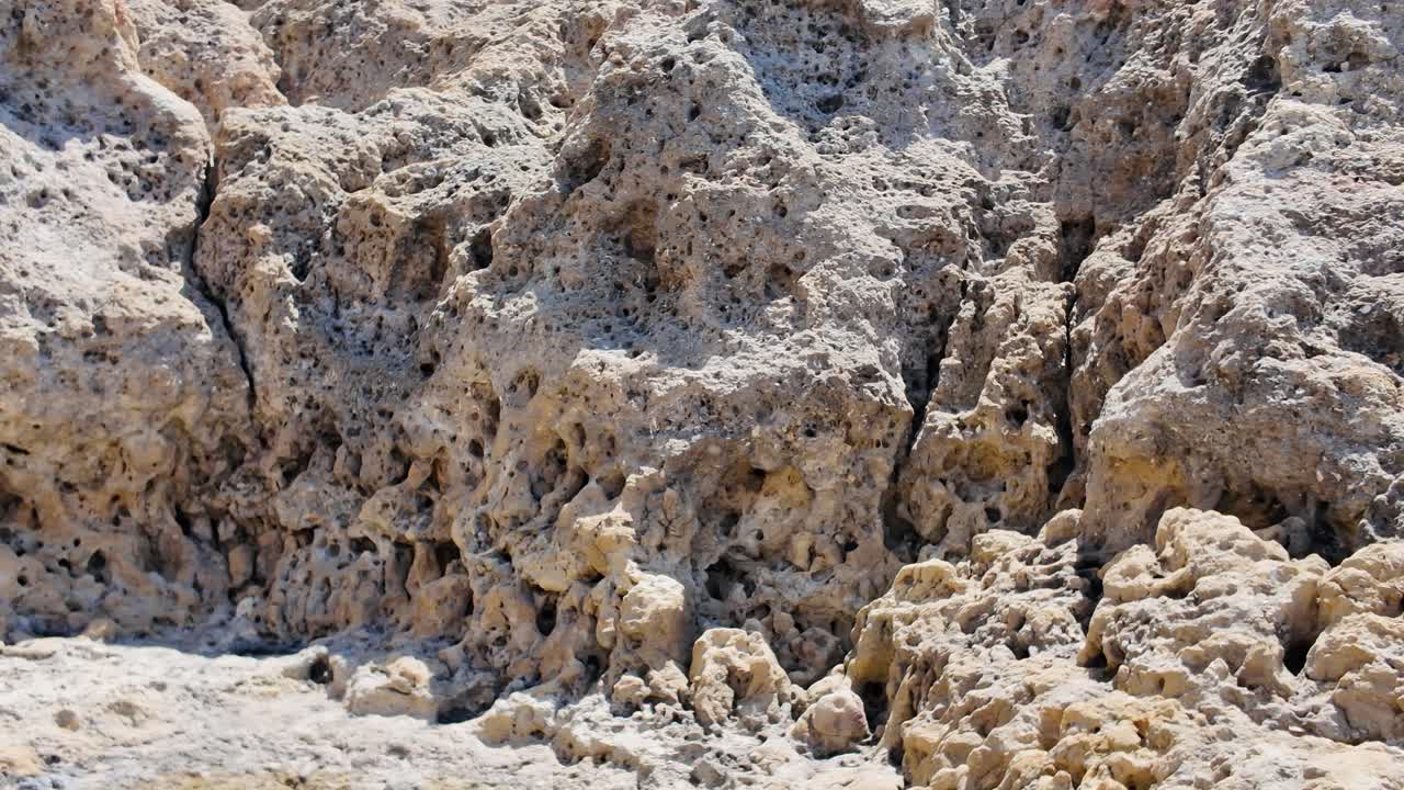 Close up of weathered and eroded rocks showing intricate patterns and textures, in the beautiful Algarve region of Portugal. Pan Left