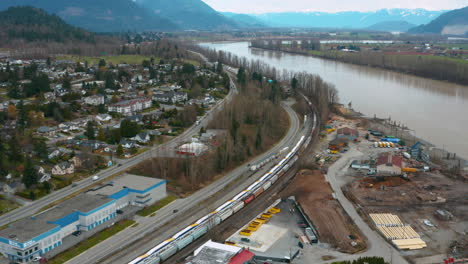 aerial over mission, bc, as a train travels along the shore of the fraser river