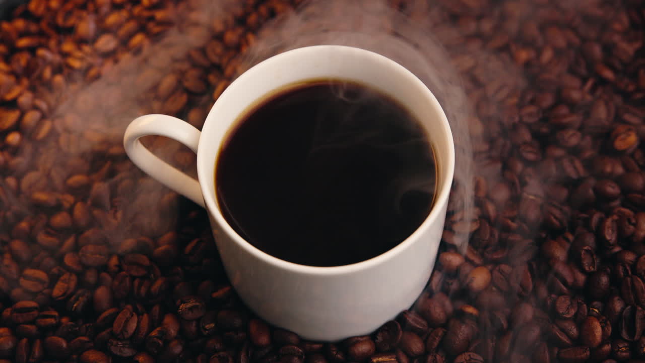 Taza de café caliente sobre granos de café tostados