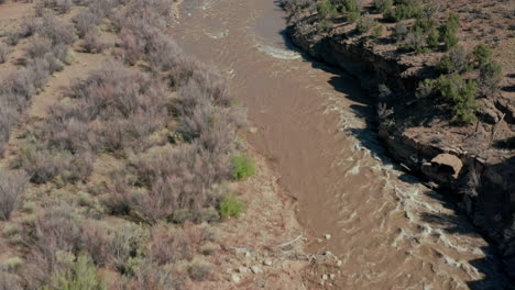 Aerial-view-over-river-panning-up-to-desert-valley-during-spring