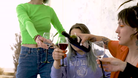 close up of a girl with tattoos and dreadlocks pouring wine for friends during a fun party at home