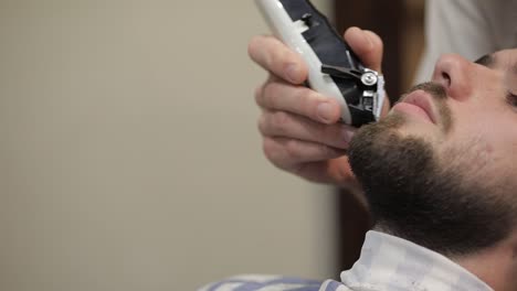 client with black beard during beard shaving in barber shop. groom, masculine