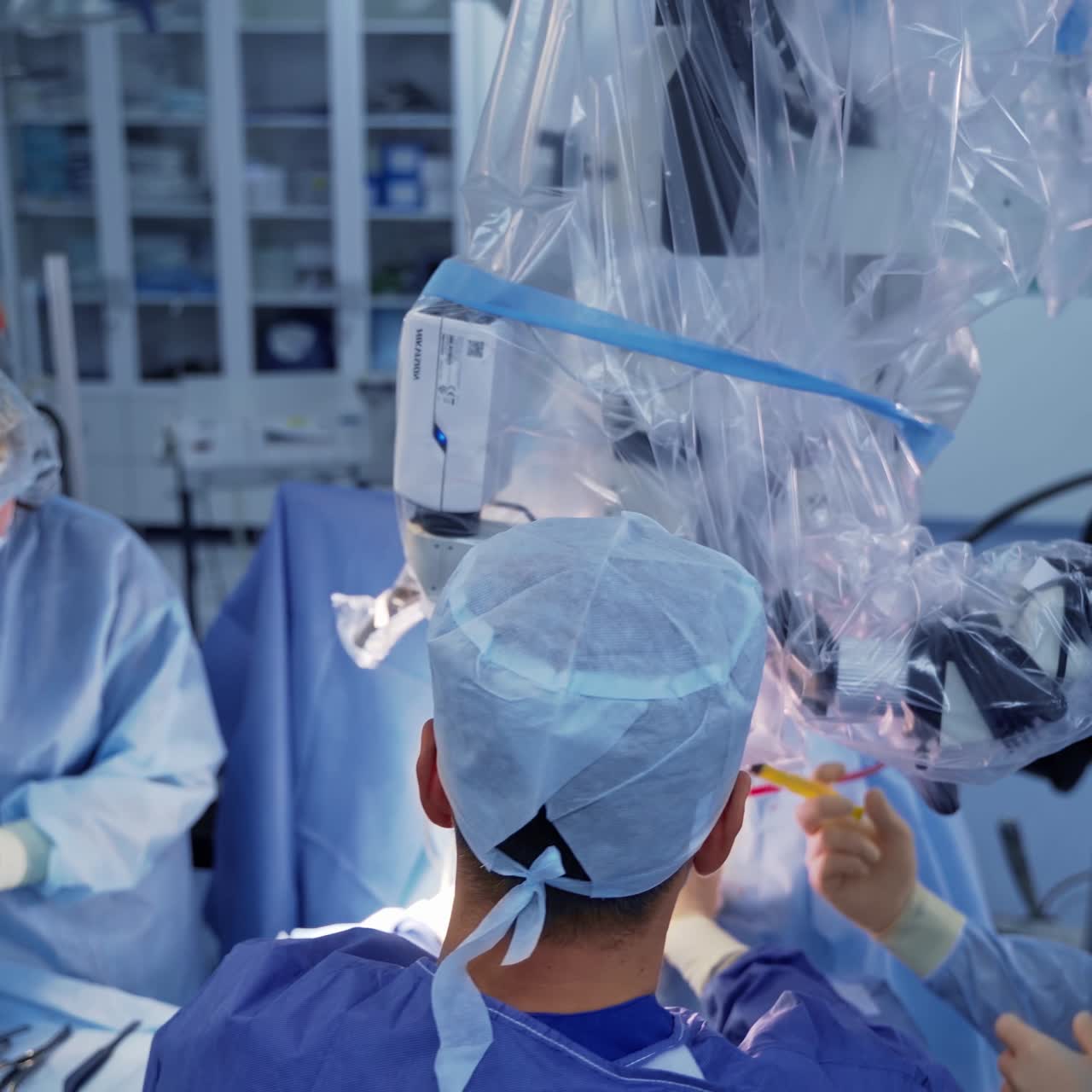 Doctors with microscope. Team of medical workers in blue uniform making operation to a patient while looking through the microscope. Top view.