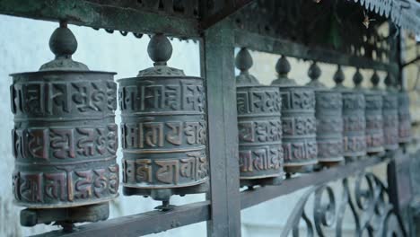ruedas de oración budistas tibetanas de nepal en el templo del mono en katmandú, primer plano de ruedas de oraciones girando, símbolo religioso utilizado para orar en un templo budista, un lugar turístico popular