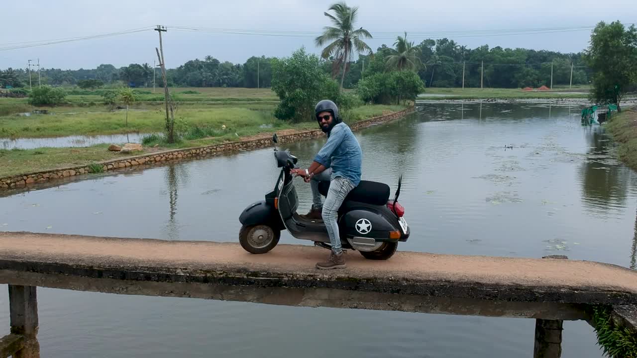 Motorbike rider crossing a village bridge,India,Crossing river,Aerial shot,Posing