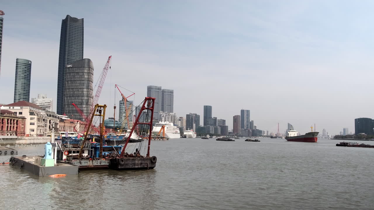 Bustling Huangpu River with a mix of cargo and passenger boats, active cranes, and skyscrapers in the background