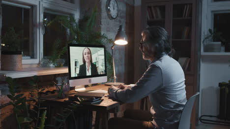 man having a video call with a woman on a desktop computer at night