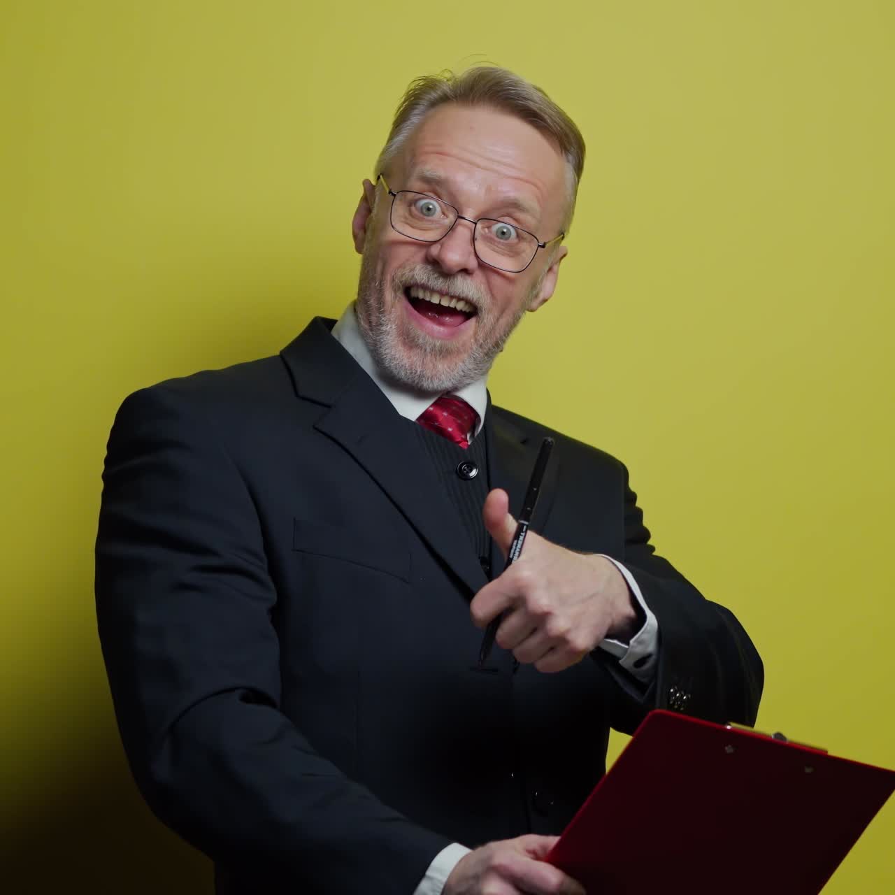 Happy elderly businessman with folder. Grey-bearded senior man is writing on paper on yellow background. Positive emotions.