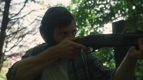 young caucasian with earmuffs shooting in the forest with shotgun weapon