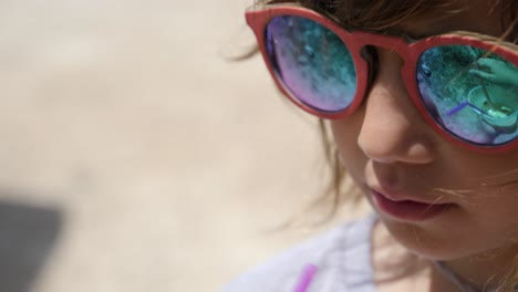 cerca de una linda niña con gafas de sol tomando una copa en la playa de vacaciones