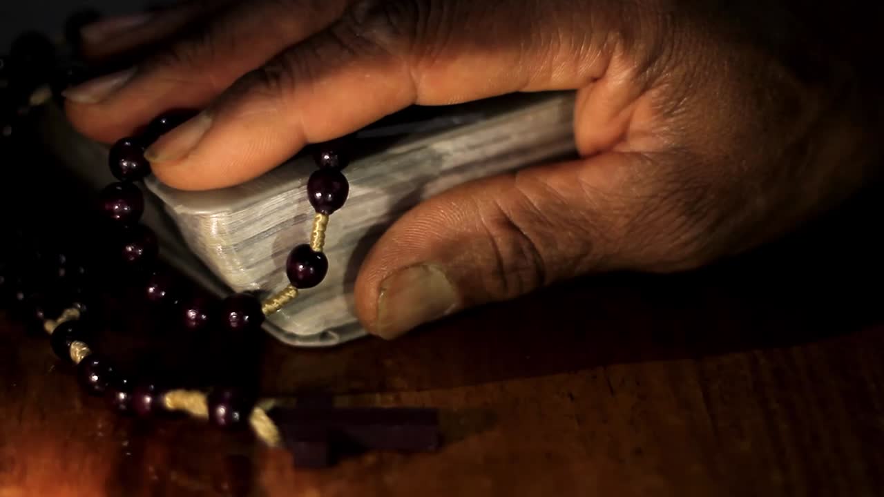 성경과 함께 손으로 신에게 기도하고 검정색 배경으로 기도하는 캐리비안 남자 스톡 비디오