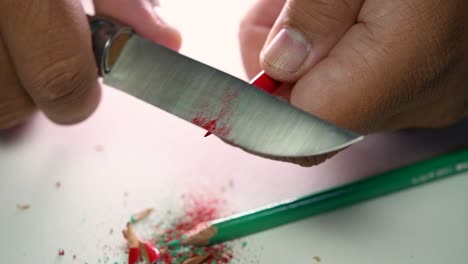 Footage-of-hands-slowly-sharpening-a-pencil-and-some-coloured-pencils-with-a-sharp-knife