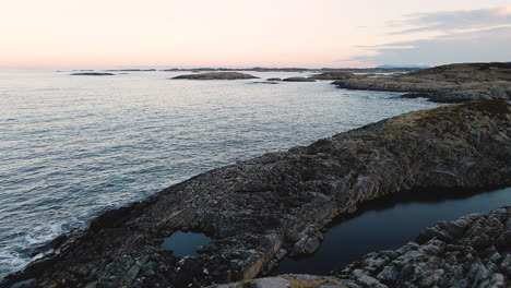 natural rock formation by the ocean shore in norway - aerial drone shot