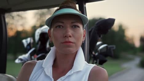 golf woman looking camera at nature. beautiful golfer sit in buggy car on course