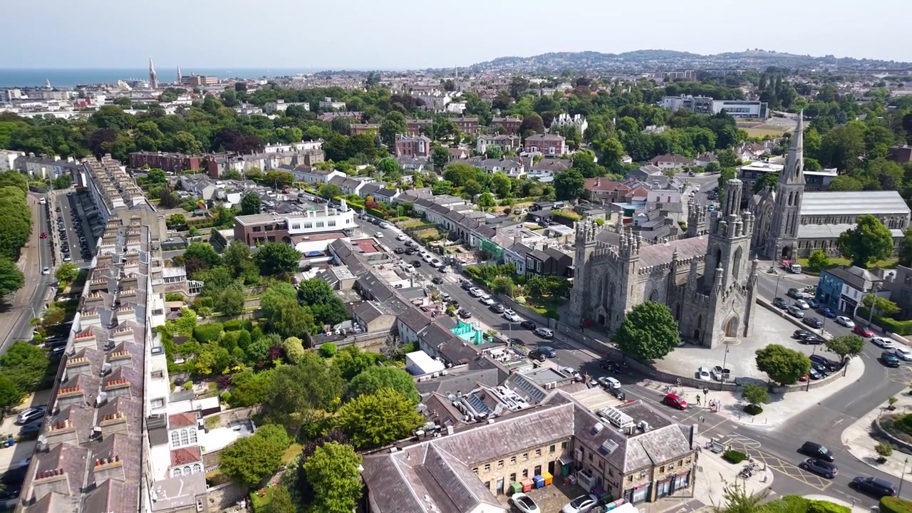 Edificio della Chiesa di Monkstown e panoramica aerea con drone che si allontana su Dun Laoghaire con parco ed edifici. Irlanda