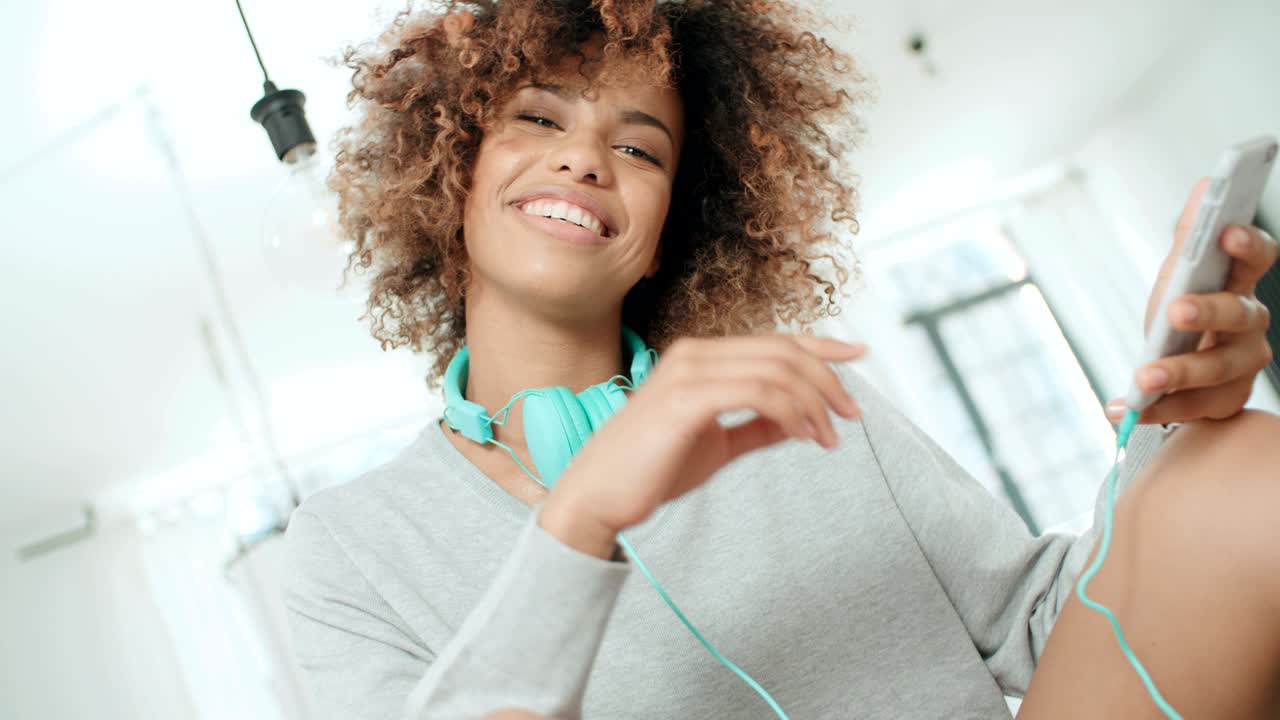 Bella giovane donna afroamericana che messaggia al cellulare a casa.